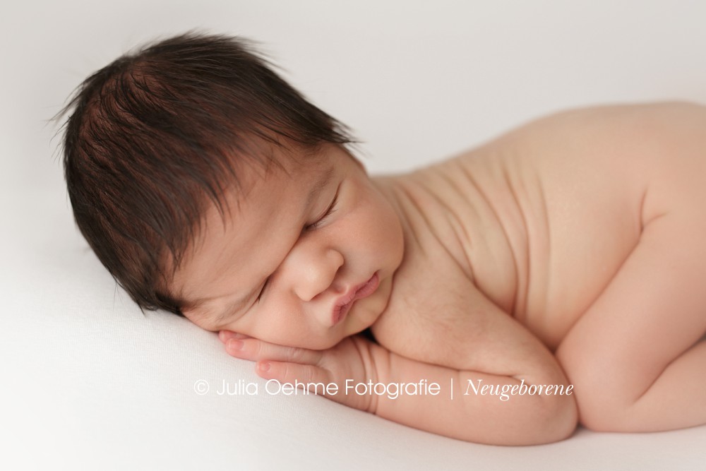 baby schläft bei fotoshooting in leipzig auf weißer decke auf dem bauch