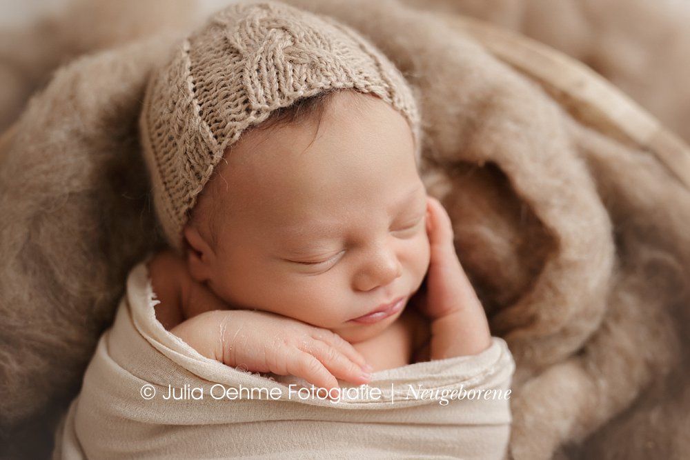 baby junge liegt eingewickelt in großer holzschale bei neugeborenenshooting julia oehme leipzig