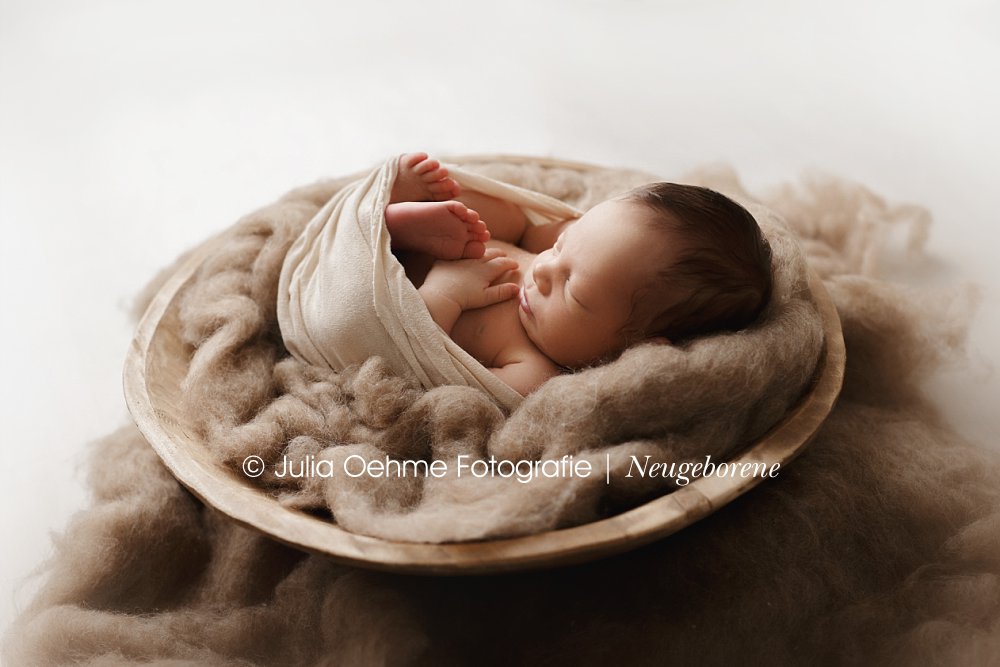 baby junge liegt eingewickelt in großer holzschale bei neugeborenenshooting julia oehme leipzig