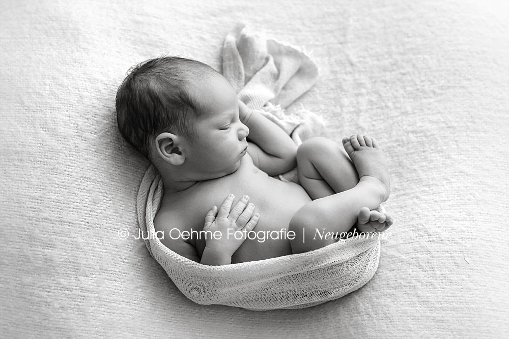 neugeborenenfotoshooting mit neugeborenem jungen natürlich in ein tuch gewickelt bei julia oehme fotografie in leipzig